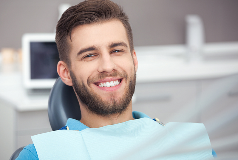 Patient smiling in a dental chair after receiving dental implant restoration from Dr. James A. Vette, DDS in Germantown, MD